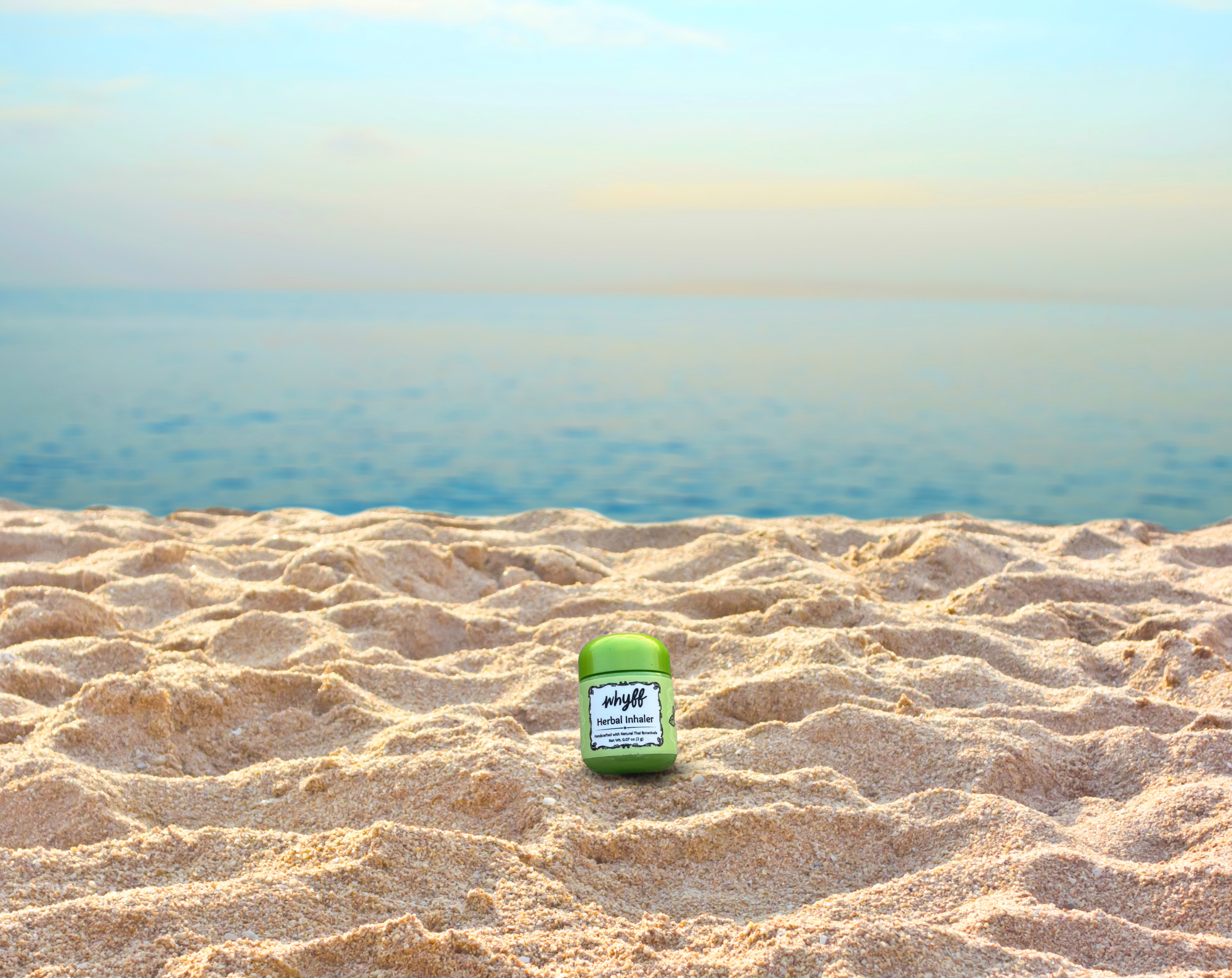 Green jar with a label on a sandy beach